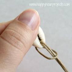 a hand holding a string with an object in it's middle and one end