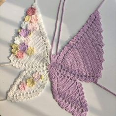 two crocheted butterflies sitting on top of a white table next to each other