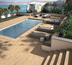 an outdoor swimming pool with lounge chairs and tables next to the water's edge