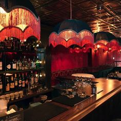 a bar with many bottles on the shelves and lights hanging from the ceiling above it