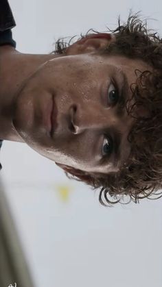 a man with curly hair is staring at the camera