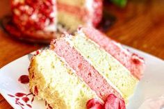 a piece of cake with strawberries on it sitting on a plate next to a slice of cake