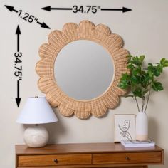 a mirror sitting on top of a wooden dresser next to a lamp and potted plant