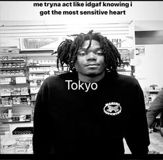 a young man with dreadlocks standing in front of a store display case and looking at the camera