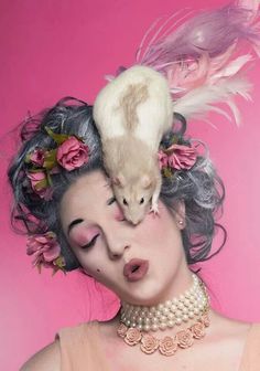 a woman with an animal on her head and flowers in her hair is posing for the camera