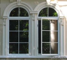 an image of two windows that are on the side of a building with trees in the background