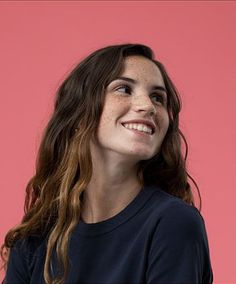 a woman with freckled hair smiles at the camera while wearing a black shirt