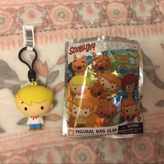 a keychain with a cartoon character on it next to a bag clip that is attached to a bed