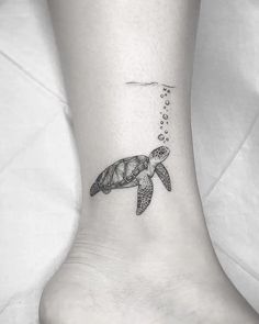 a turtle tattoo on the ankle with bubbles coming out of its mouth and an ocean wave coming