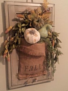 a burlap sack filled with fall foliage and pumpkins hangs on the wall