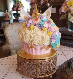 a cupcake decorated with pastel flowers and an unicorn's horn on top