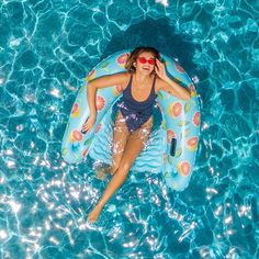 a woman laying on top of an inflatable raft floating in a pool with blue water