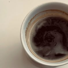 a white cup filled with liquid on top of a table