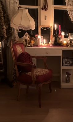 a room with a desk, chair and candles on it in front of a window