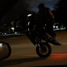 a man riding on the back of a motorcycle at night