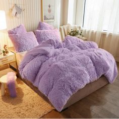 a bed with purple comforters and pillows in a room