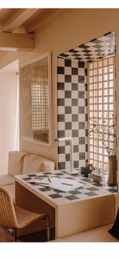 a living room with a checkered wall and table in the middle, chairs around it