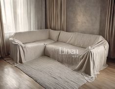 a living room with a couch covered in a blanket next to a curtained window