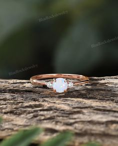 a white opalite ring sitting on top of a piece of wood with leaves in the background