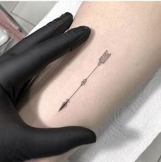 a small arrow tattoo on the thigh