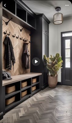 an entry way with black cabinets and coat racks on the wall next to a potted plant