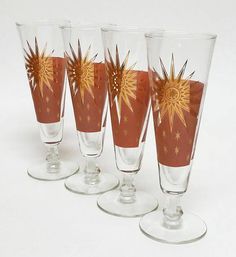 four wine glasses with designs on them sitting side by side in front of each other