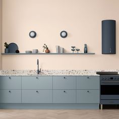 a kitchen with an oven, sink and shelves on the wall above it that are painted blue