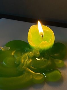 a green candle sitting on top of a white table