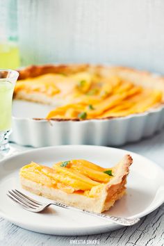 a piece of quiche on a plate with a fork and glass of green juice