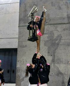 the cheerleaders are doing tricks in front of the building with their trophy and trophies