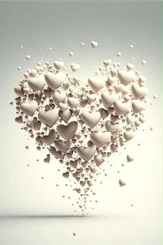 a heart made out of white hearts floating in the air with water droplets on it