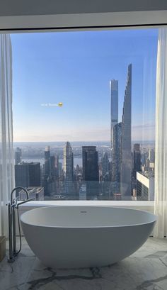 a large bathtub sitting in front of a window overlooking a cityscape and skyscrapers