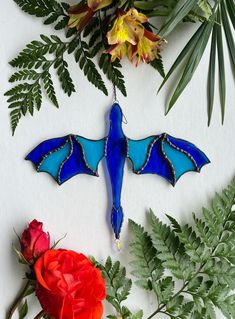 a blue glass bird ornament sitting on top of a table next to flowers