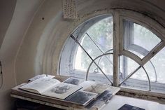 an open book sitting on top of a wooden table next to a window with glass panes