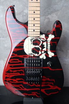 a red and black guitar with a skull on it