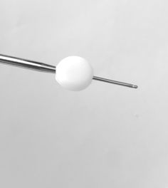 a white ball is hanging from the end of a metal rod on a gray background