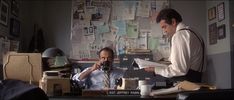 two men sitting at a desk in an office