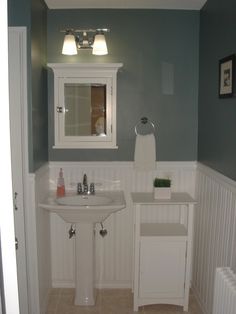 a white sink sitting under a bathroom mirror next to a radiator in a bathroom