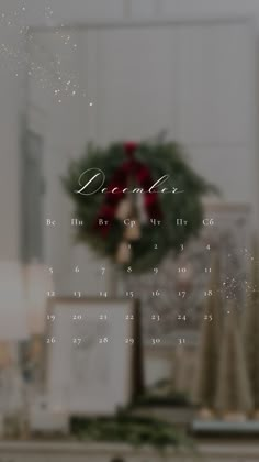 a christmas wreath is on top of a table in front of a window with the words december written across it