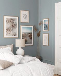 a bedroom with blue walls and pictures on the wall above the bed, along with a lamp