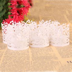 three white paper crowns sitting on top of a table next to flowers and newspaper pages