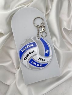 a keychain with two different colors on it sitting on a white satin background