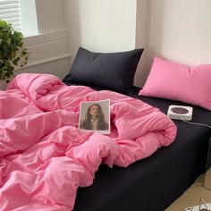 an unmade bed with a pink comforter on it and a photo of a woman