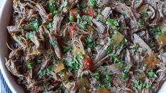 a white bowl filled with shredded meat and veggies on top of a blue towel