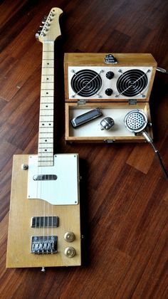 an electric guitar sitting on top of a wooden floor next to a box with other musical instruments