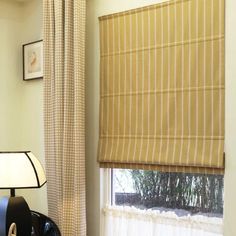 a bedroom with a window covered in roman shades