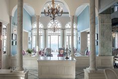 an elegant dining room with chandelier and chairs in front of large windows that look out onto the ocean