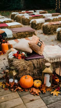 hay bales and pumpkins are arranged on the ground in front of rows of candles