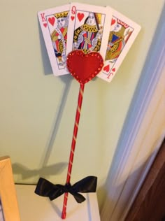 a red and white striped stick with playing cards on it sitting on top of a table