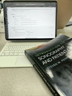 a laptop computer sitting on top of a desk next to a book titled songcrafty and patient